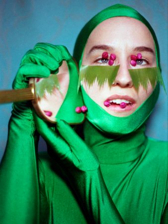 Beyond Me - Bob Jones: Person mit grüner eng anliegender Kleidung inklusive Kopfbedeckung mit pinkfarbenen Perlen an Mund, Augen und Händen